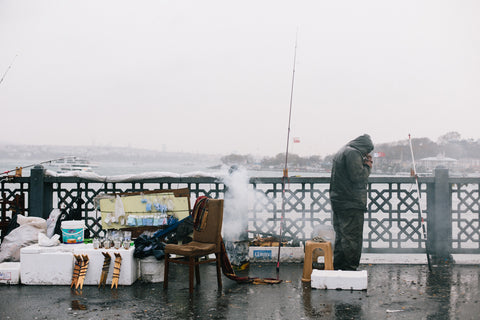 A fisherman on the Galata Bridge on a rainy day in Istanbul