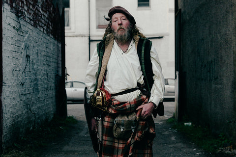 A man in a kilt stands in an alleyway in Glasgow, Scotland