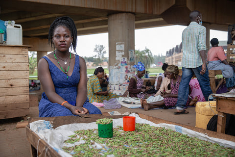 A woman sits by a tray full of grasshoppers (nsenene), preparing them to be fried in Kampala, Uganda