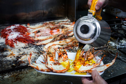 Melted butter being poured over freshly grilled lobsters at Cervejaria Ramiro seafood restaurant in Lisbon, Portugal