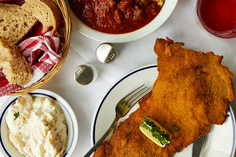 Plates of schnitzel and goulash on a table at Róma Ételbár restaurant in Budapest, Hungary
