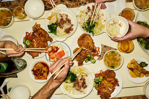 From Fare magazine's Issue 16: Taipei, a top down view of a table full of Taiwanese food, with lots of hands using chopsticks to eat