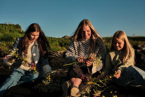A group of two women and a girl making flower crowns for a midsummer celebration in North Norway