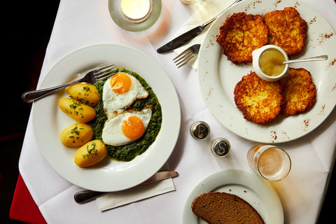 A top down view of a plate of fried eggs, creamed spinach (Blubb-Spinat), and boiled potatoes at Diener Tattersall in Berlin, by Sam A. Harris